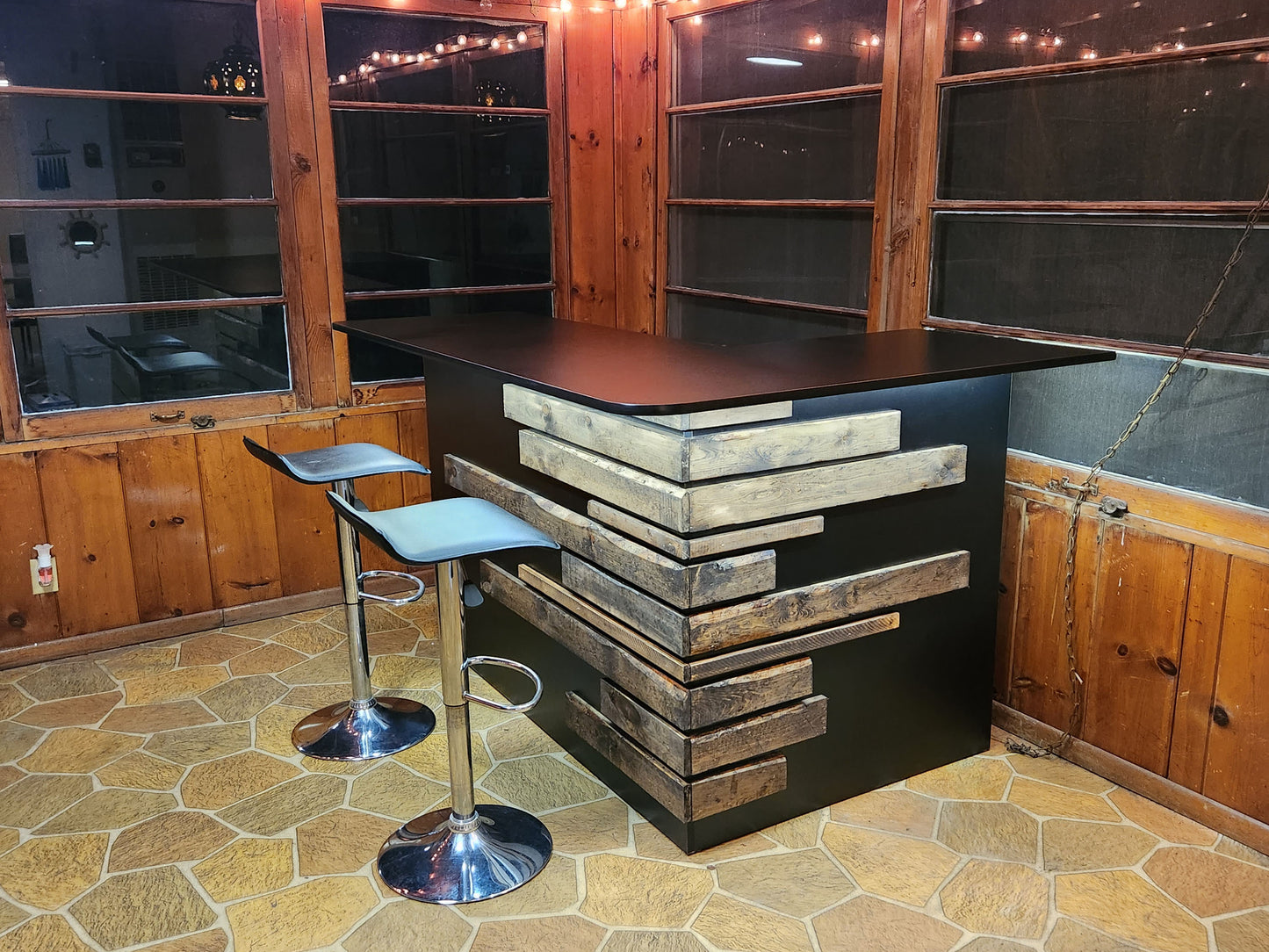 Rustic home bar crafted from reclaimed wood, featuring distressed finishes and ample storage shelves for bottles and glassware, creating a cozy and inviting atmosphere for entertaining guests