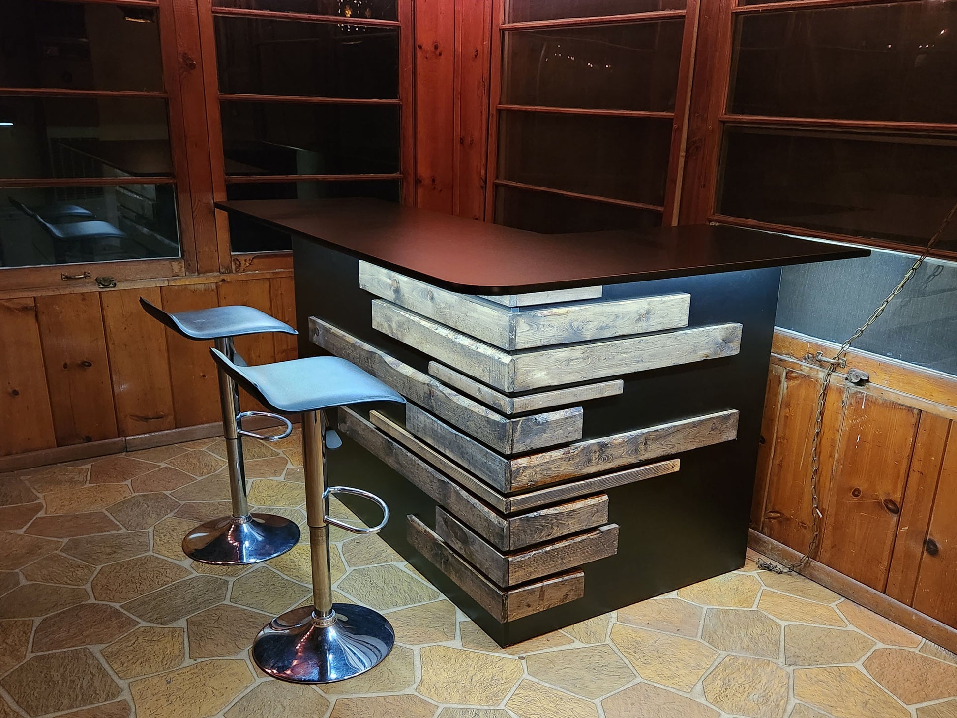 Rustic home bar crafted from reclaimed wood, featuring distressed finishes and ample storage shelves for bottles and glassware, creating a cozy and inviting atmosphere for entertaining guests